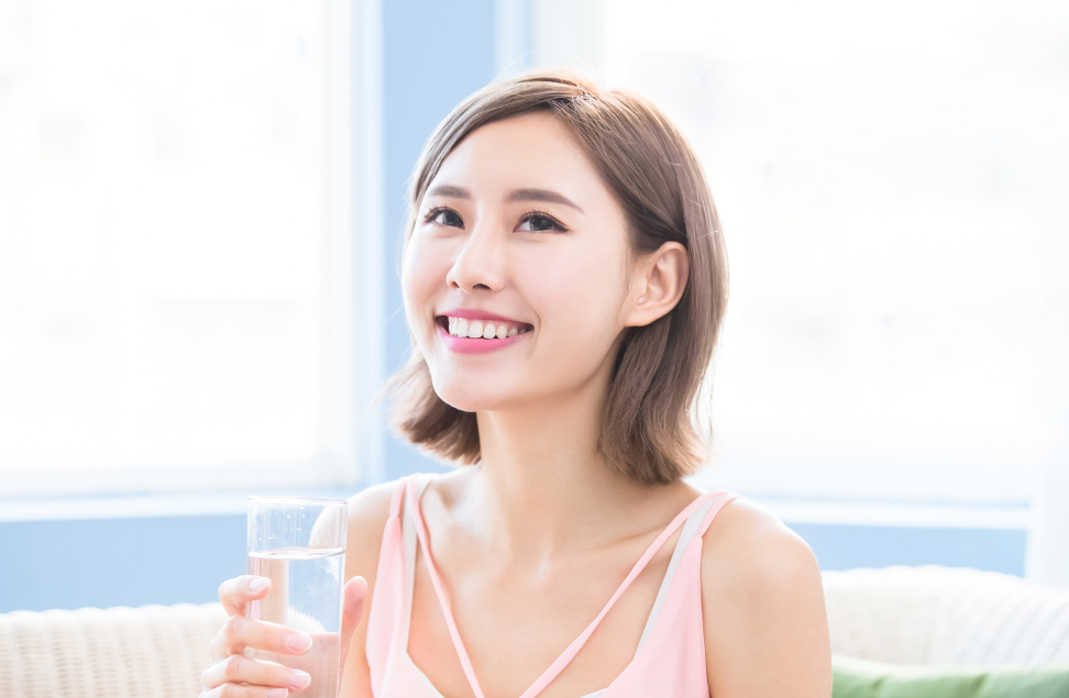 グラスの水を持って微笑んでいる若い女性