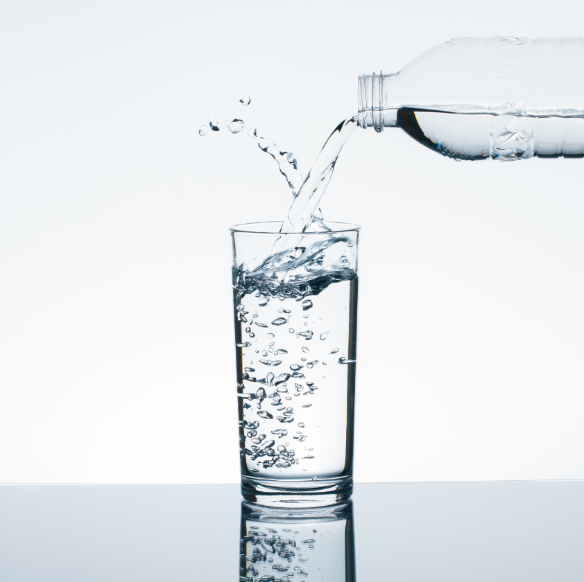 グラスにペットボトルの水を注いでいる