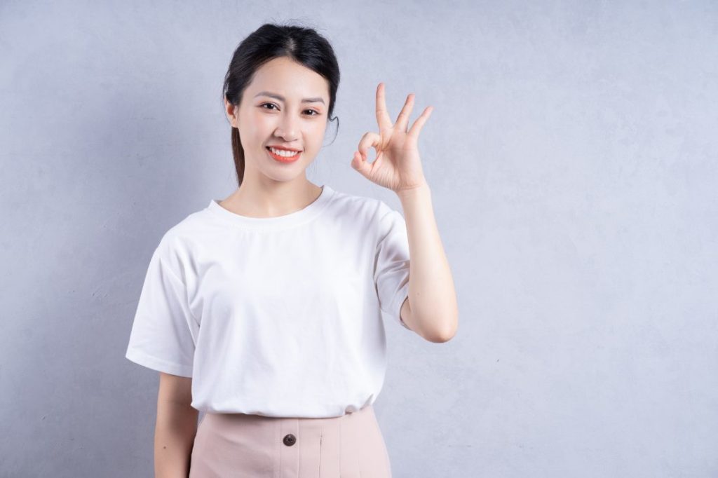 左手でOKマークで微笑む若い女性