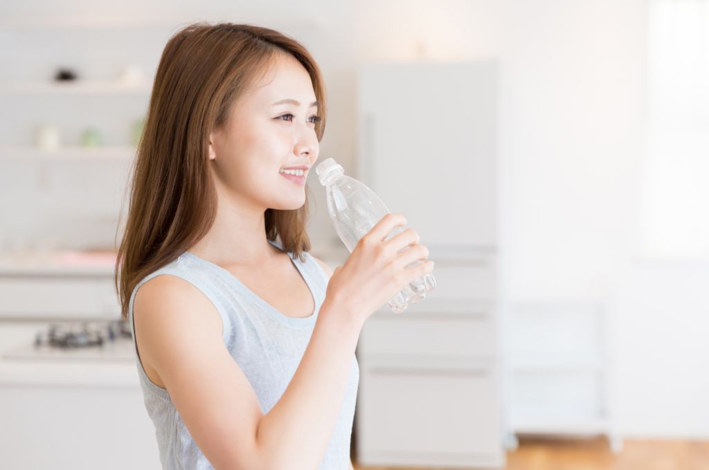 ペットボトルの水を飲もうとしている若い女性