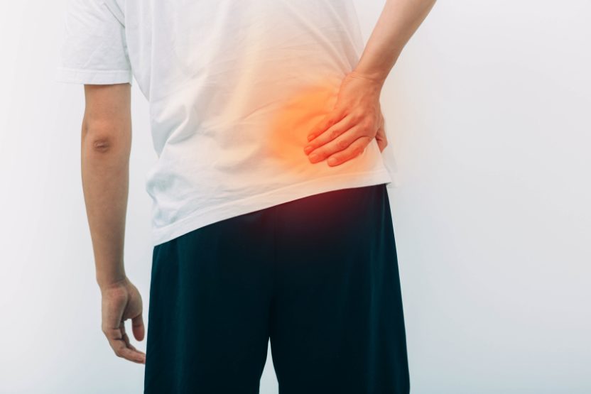 安いマットレス　右手で腰痛を抑えている男性