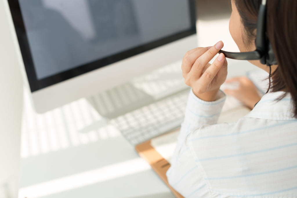 パソコン画面の前で応答している若い女性オペレーターの後ろ姿