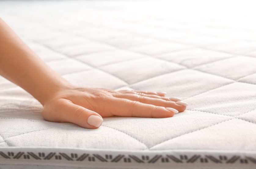 マットレスの上に左手を添えている女性の手