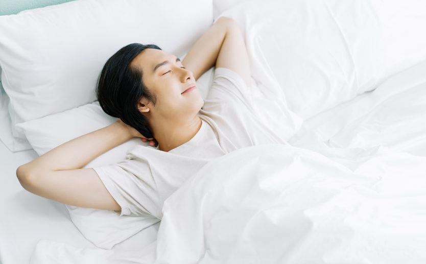 マットレスの上で気持ちよさそうに寝ている若い男性