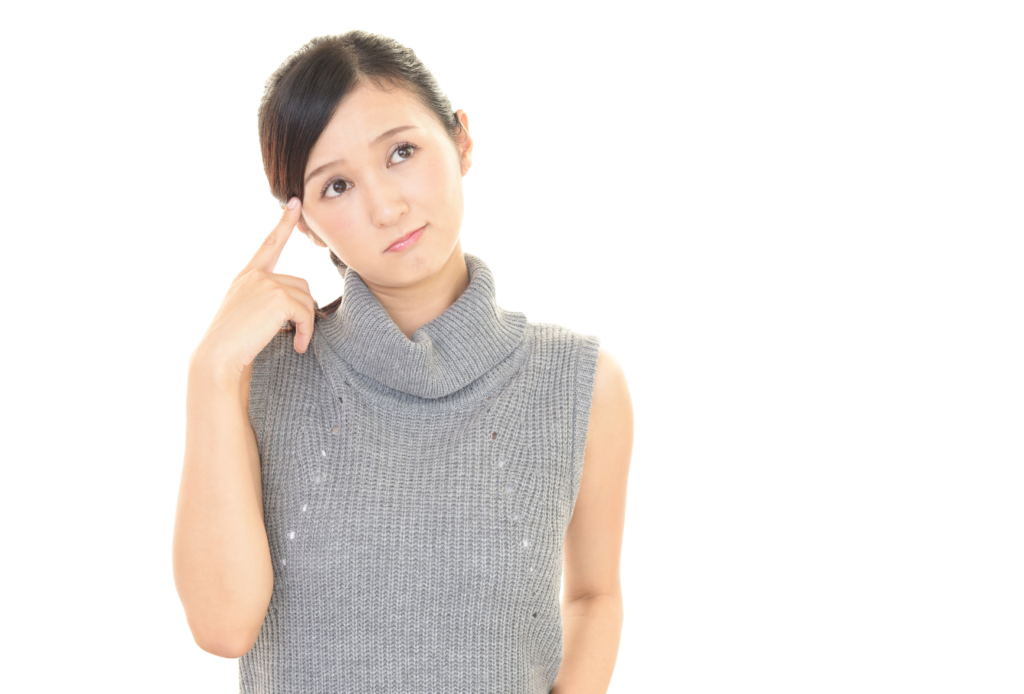 右人差し指を頭に当てて考えている若い女性