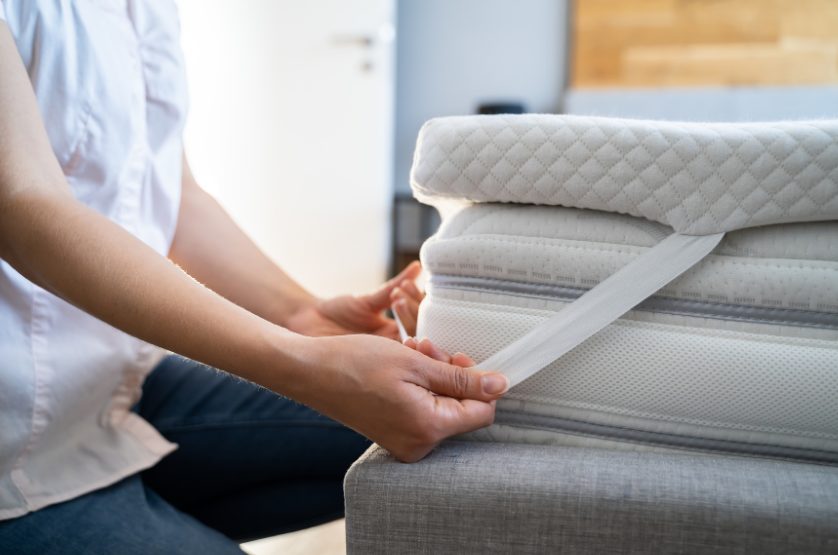 重ねたマットレスの厚みを見ている女性