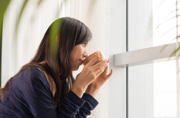 両手でカップを持ちコーヒーを飲んでいる女性