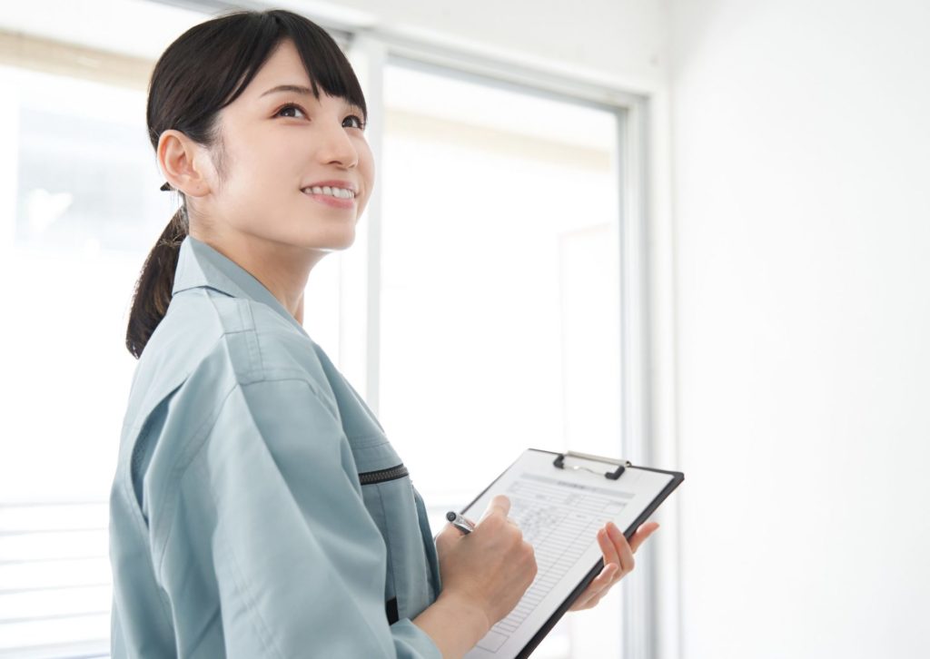 クリップボードとボールペンを持ち、部屋をチェックしている若い女性業者