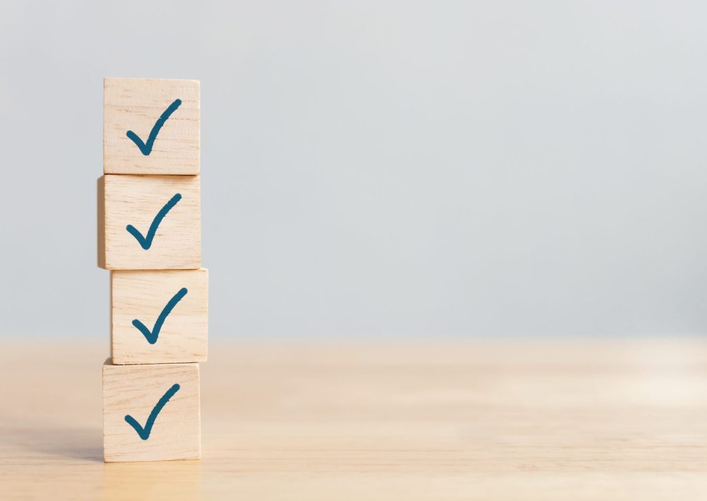 机の上にチェックマークの入った4つの四角い積み木が重なっている