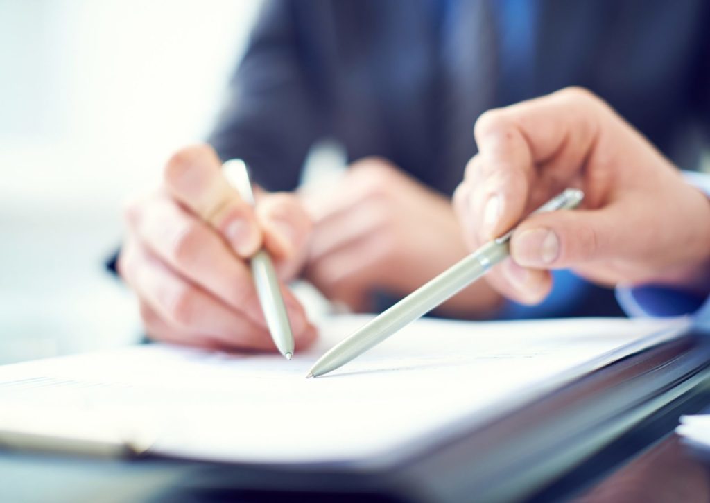 書類の上で、上司が部下にペンを指して教えている