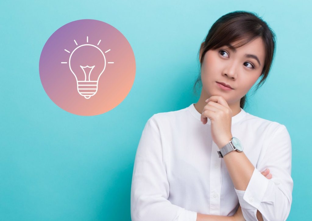 左手を顎に着けて考えている白いシャツの女性