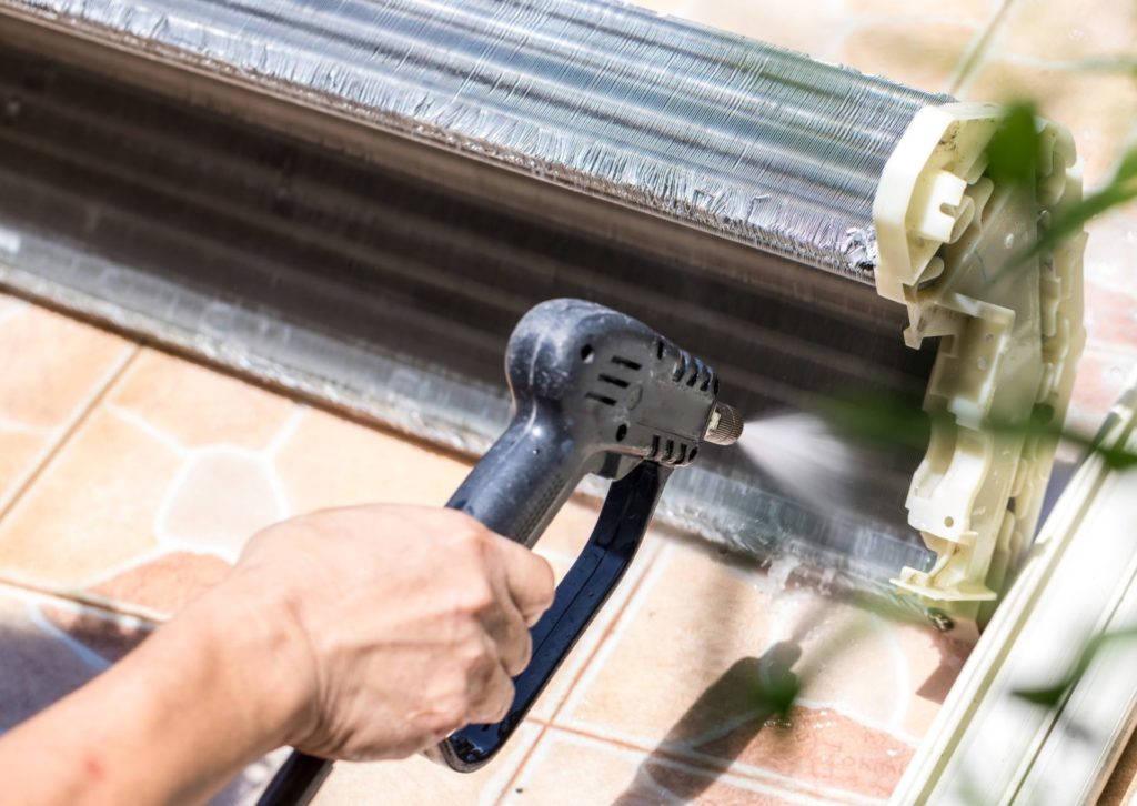 取り外したエアコン内部を高圧洗浄している業者