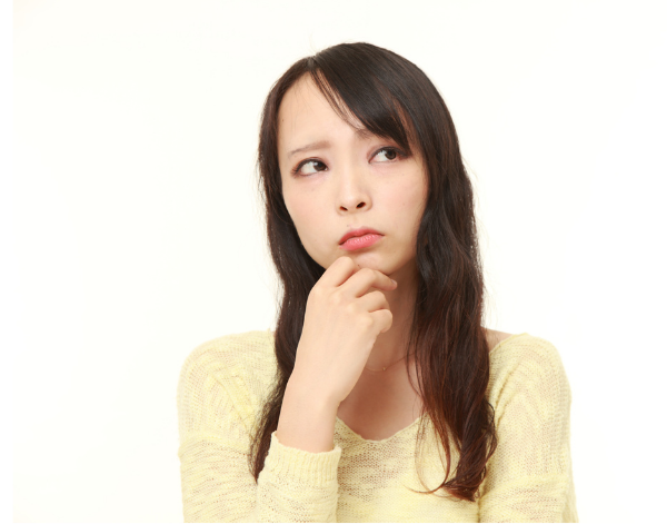 右手を顎に当て考え事をしている若い黄色のワンピースを着た女性