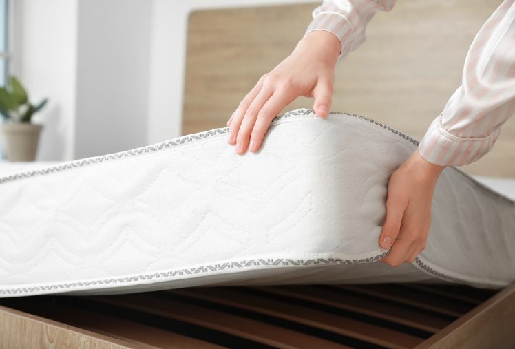 女性がマットレスを持ち上げて厚みを示している