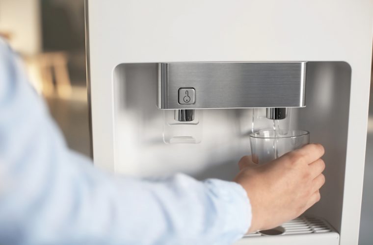 ウォーターサーバーから水をコップに注いでいる