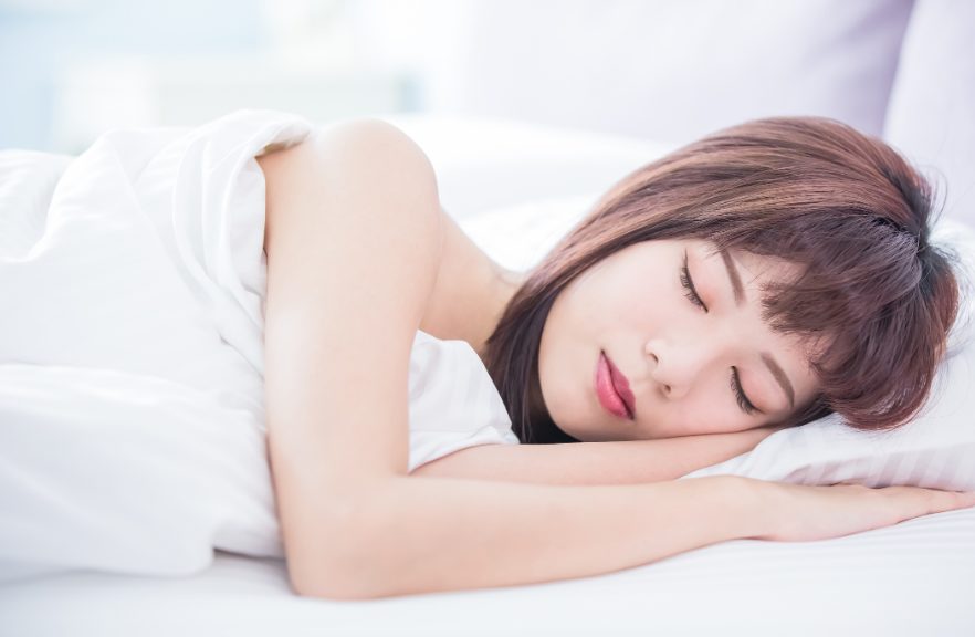 マットレスの上で気持ちよさそうに寝ている若い女性